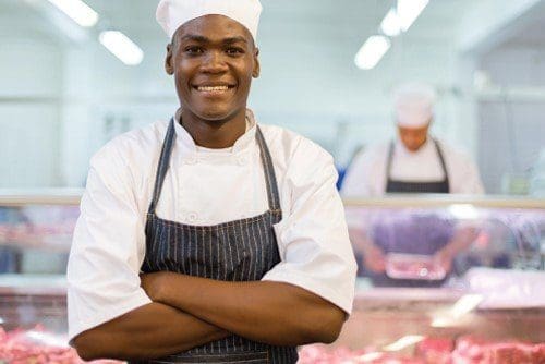 black man in butchery uniform smiling
